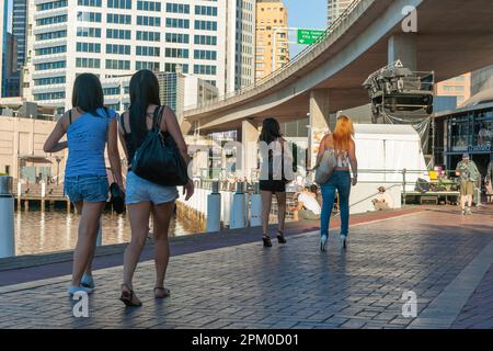 Sydney Australia - January 25 2011; two pairs of women walking in shade on side of harbour under bridge Stock Photo
