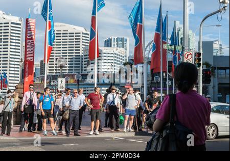 Sydney Australia - January 25 2011; People waiting standing on curb in variety of dress at crossing  city street to Pyrmont Bridge on Darling Harbour. Stock Photo