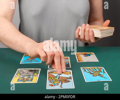 Lodz, Poland April 07 2023 Tarot reader teller spreading playing cards on desk, reading future, fortune. Stock Photo