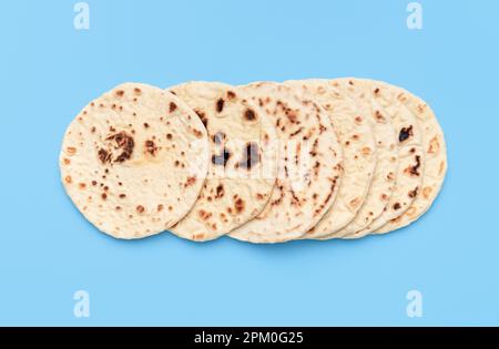 Above view with several naan breads, minimalist on a blue table. Homemade indian flat bread, in bright light, isolated on a vibrant background Stock Photo