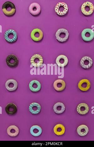 Round donuts food with different decoration on a solid purple pink background Stock Photo