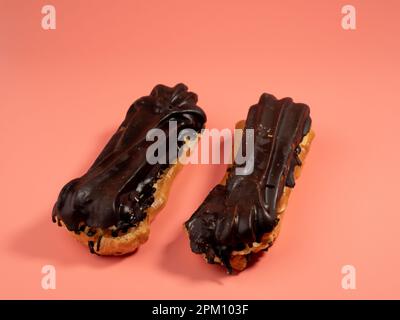 Delicious chocolate eclairs isolated on pink background. Eclairs Close-up. Stock Photo