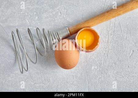 Two beige chicken eggs and a rare beater for beating Stock Photo