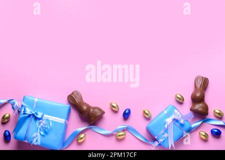 Chocolate bunnies, Easter eggs in foil and gift boxes on pink background Stock Photo