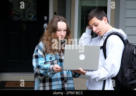 Happy young female employee discussing online project showing computer presentation to skilled team leader in eyeglasses. Friendly diverse colleagues working in pairs on laptop, using applications Stock Photo