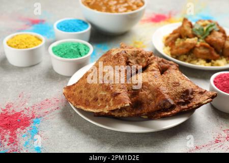 Traditional Indian food and color powders on grey table. Holi festival celebration Stock Photo