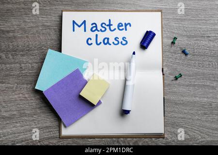 Notebook with words Master Class, felt pen, pins and sticky notes on wooden table, flat lay Stock Photo