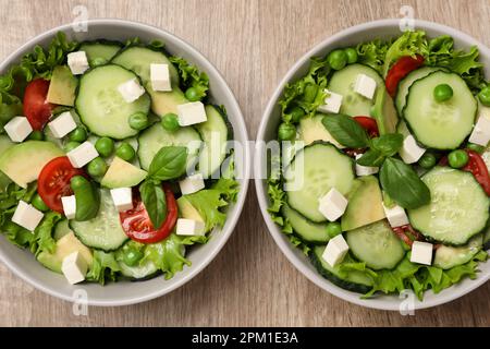 Tasty fresh salad with cucumber in bowls on wooden table, flat lay Stock Photo