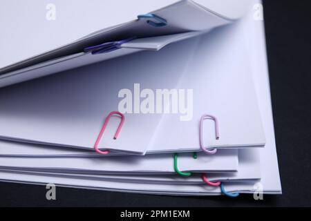 Sheets of paper with clips on black background, closeup Stock Photo