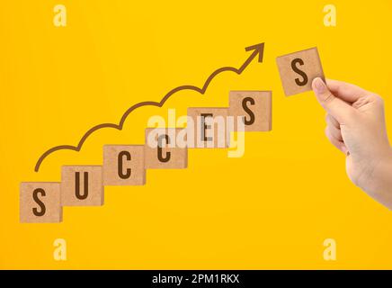 Hand putting wooden cube block with word SUCCESS, business growth concept Stock Photo