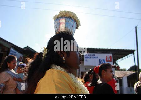 Deliserdang, Indonesia. 09th Mar, 2023. A Hindu woman from the ethnic Tamils, seen with a mouth piercing carrying a jug filled with cow's milk, held high above her head, as she walks towards the Sri Kartigay Sibolangit temple. Ethnic Tamil women, celebrate an annual festival in the month of Pangguni or Pangguni Uthiram to worship the god Muruga. Credit: SOPA Images Limited/Alamy Live News Stock Photo