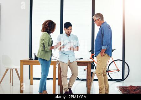 They function of leadership is to produce more leaders. a creative entrepreneur offering advice to two new colleagues in the office. Stock Photo