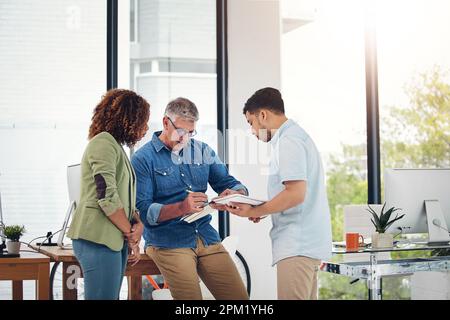 Look how I do it. a creative entrepreneur offering advice to two new colleagues in the office. Stock Photo