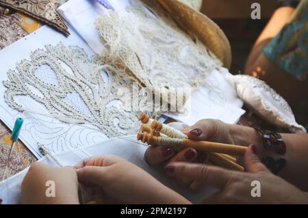 Close-up photo of a woman and a girl making lace using bobbins Stock Photo