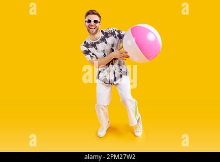 Smiling happy guy in sunglasses holding inflatable sea ball Stock Photo