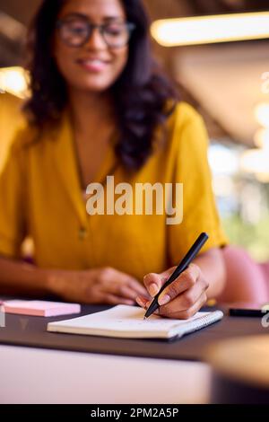 Mature Businesswoman Working At Desk In Office Writing In Notebook Stock Photo