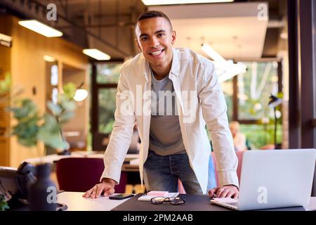 Portrait Of Young Businessman Working Standing At Desk In Office Stock Photo