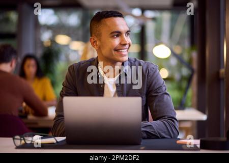 Young Businessman Working On Laptop At Desk In Office Stock Photo