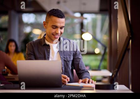 Young Businessman Working On Laptop At Desk In Office Making Notes Stock Photo