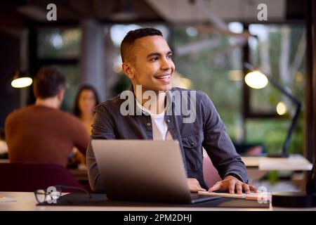 Young Businessman Working On Laptop At Desk In Office Making Notes Stock Photo