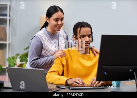 Portrait of two young people man and woman working together in IT development office and using computer Stock Photo