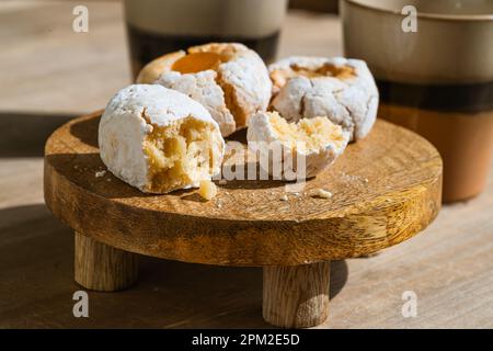 Italian amaretti cookies, almond biscuits and cups of hot chocolate on wooden table. Sunlight with harsh shadows. Traditional simple Christmas cookies Stock Photo