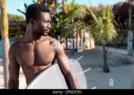 Happy african american man holding surfboard at beach Stock Photo