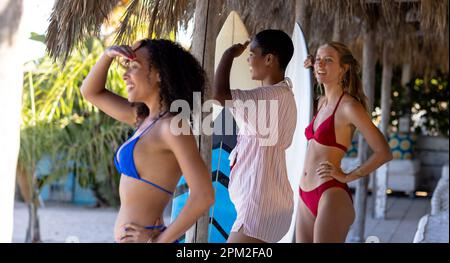 Happy diverse female friends holding surfboards at beach Stock Photo