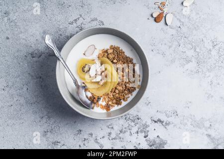 Yogurt granola bowls with kiwi fruit on grey board,  top view. Healthy vegetarian breakfast meal Stock Photo