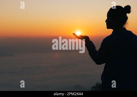 Silhouette of woman hand praying spirituality and religion,  Woman raising his hands in worship. Christian Religion concept background. Stock Photo