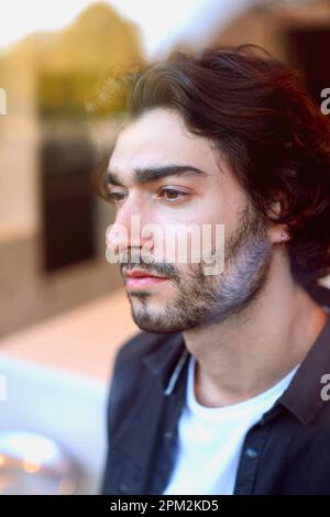 Thoughtful Young Man At Home In Kitchen Looking Out Through Window Stock Photo