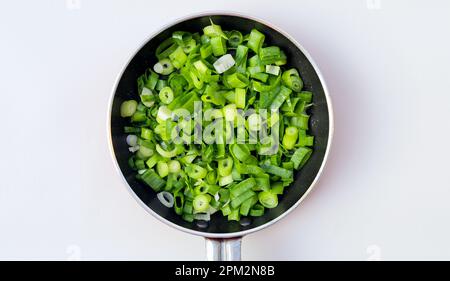 Chopped spring onions or chives isolated in frying pan on white background, top view Stock Photo