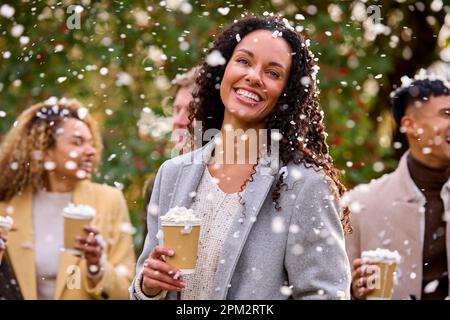 Group Of Friends Wearing Coats Standing Outside In Snow Holding Takeaway Hot Chocolate Drinks Stock Photo