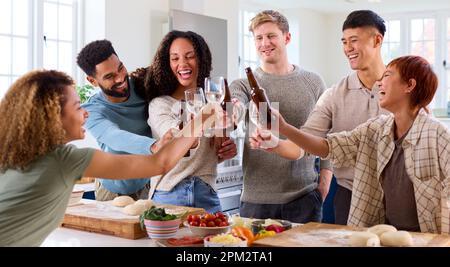 Group Of Friends At Home In Kitchen With Drinks Making Food For Party Stock Photo