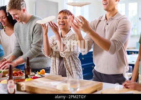 Group Of Friends At Home In Kitchen With Making Pizzas For Party Together Stock Photo