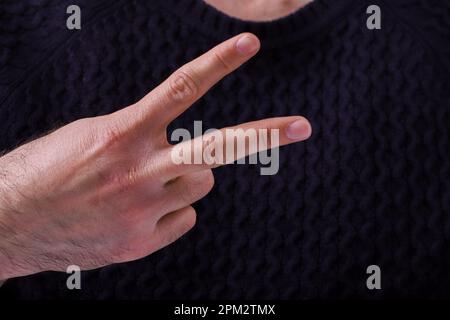 Young man making two signs with his hand. with hand making v shape over chest, showing victory or peace Stock Photo