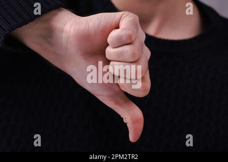 Man showing thumbs down. Negative concept. Close-up of young man's hands showing a thumbs down for dislike service. Customer service and satisfaction Stock Photo