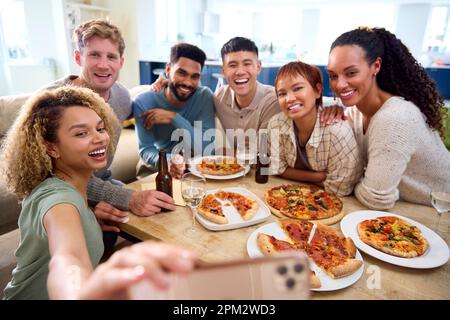 Friends Taking Selfie On Phone Having Fun At Home In Kitchen Eating Homemade Pizzas Stock Photo