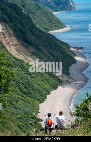 Walkers take in the view of the Coastal walk along the Jurassic  Coast between Sidmouth and Beer Beach in Devon, England.  Credit: Rob Taggart/Alamy Stock Photo