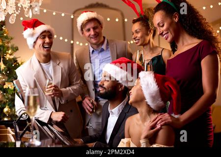 Friends At Piano Wearing Santa Hats And Reindeer Antlers Celebrating At Christmas Or New Year Party Stock Photo