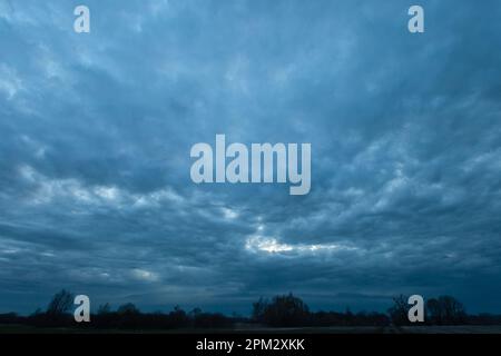 Abstract dark storm clouds over trees, spring evening view Stock Photo