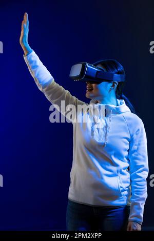 Happy asian woman using vr headset in studio with blue light Stock Photo