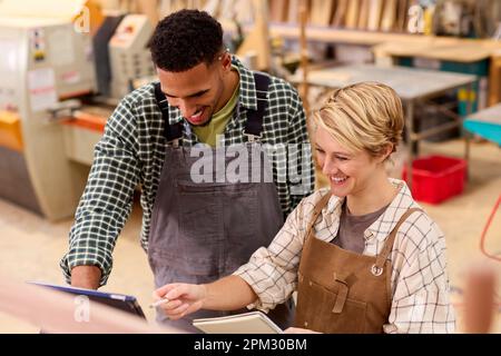 Male And Female Apprentices With Digital Tablet Working As Carpenters In Furniture Workshop Stock Photo