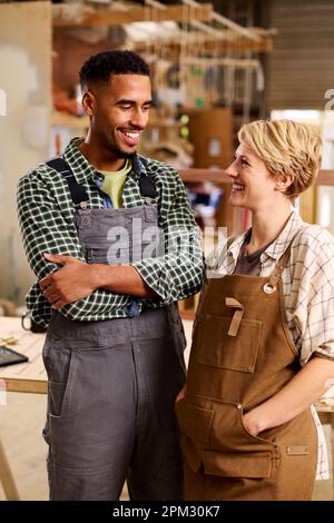 Portrait Of Male And Female Apprentices Working As Carpenters In Furniture Workshop Stock Photo
