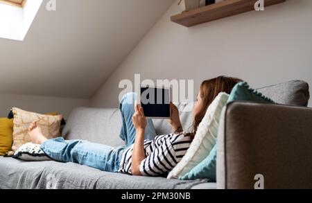 Woman using internet and digital tablet while resting at home. Stock Photo