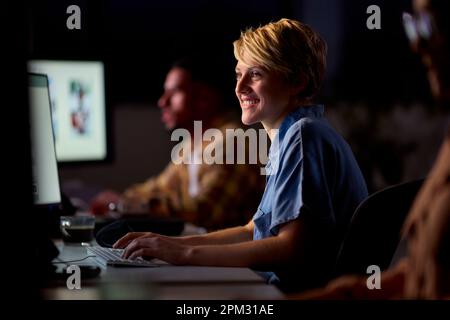 Business Team Using Computers At Desks In Office Working Late Stock Photo