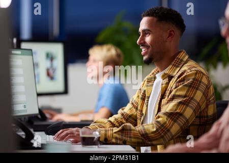 Business Team Using Computers At Desks In Office Working Late Stock Photo