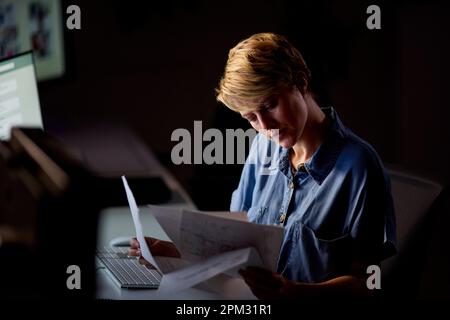 Businesswoman Working Late In Office With Face Illuminated By Computer Screen Stock Photo