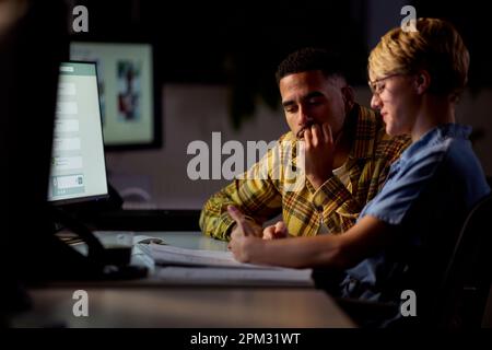 Two Business Colleagues At Desks In Office Working Late On Project Together Stock Photo
