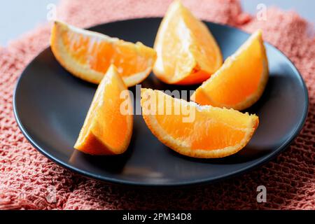 Orange slices on black plate, closeup. Selective focus. Stock Photo